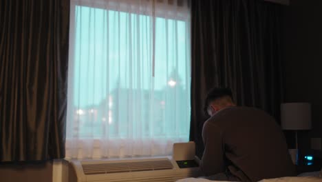 man in solitude by hotel window at dusk