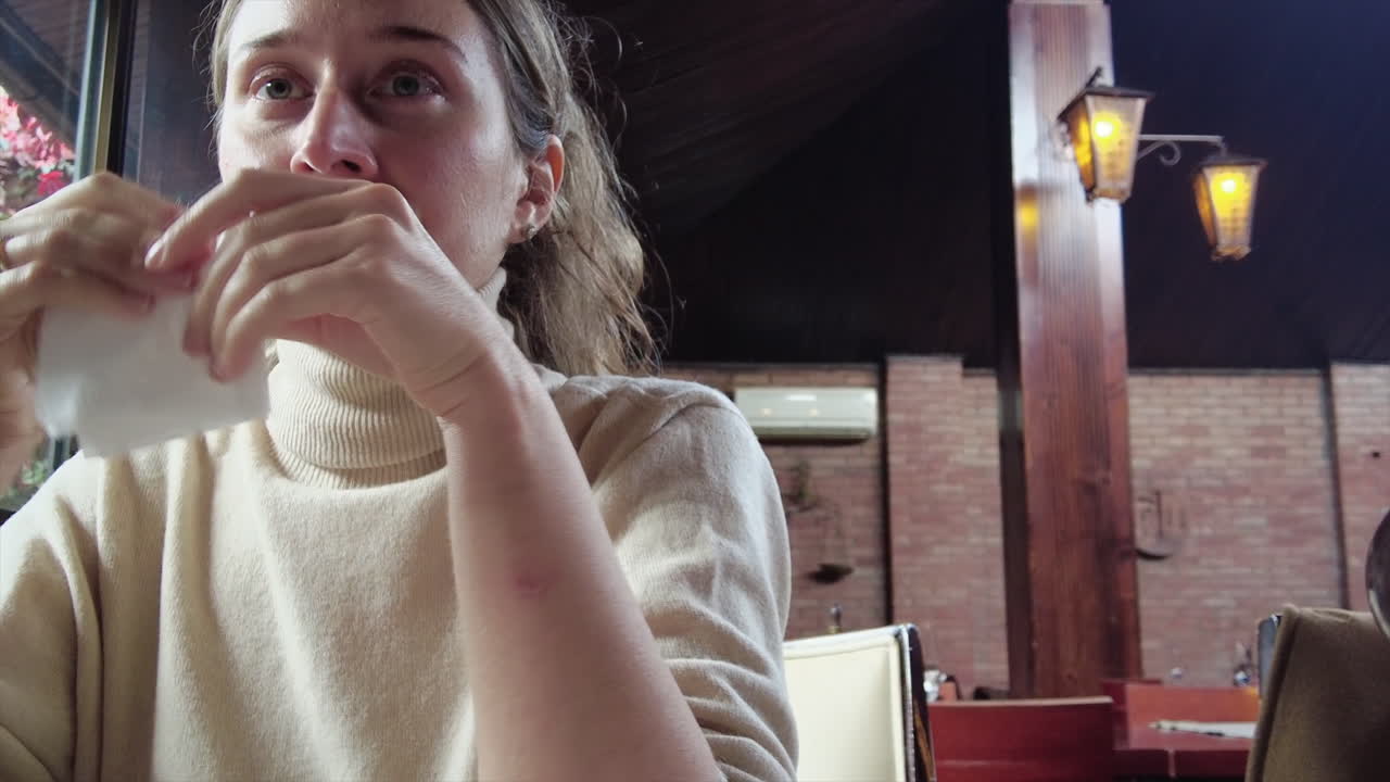 Woman sneezing at a restaurant and using white paper napkin