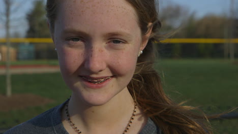 closeup portrait of a teen girl athlete smiling at camera outside at a track