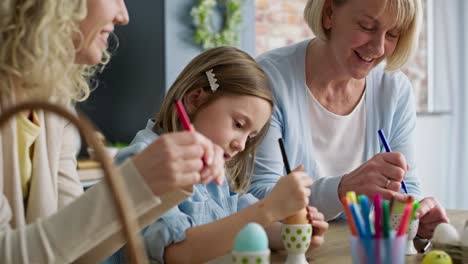 zoom in video of generations of women coloring easter eggs