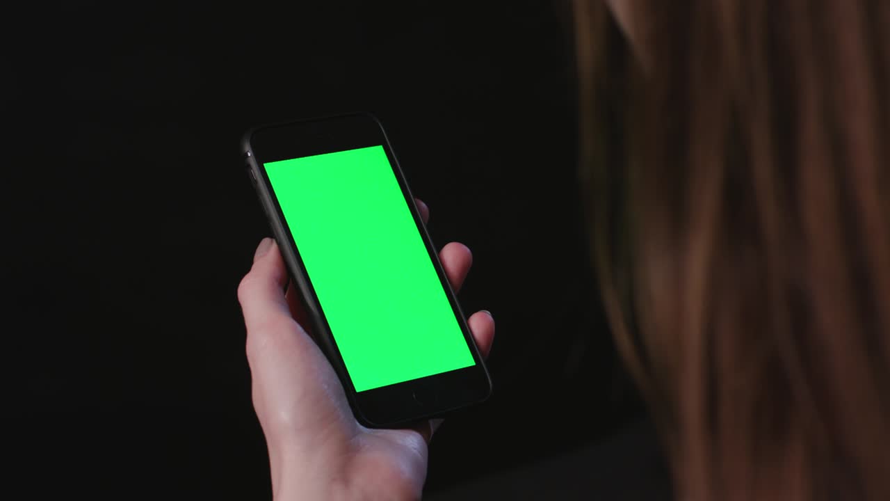 여성이 초록색 화면으로 전화를 들고 있습니다.