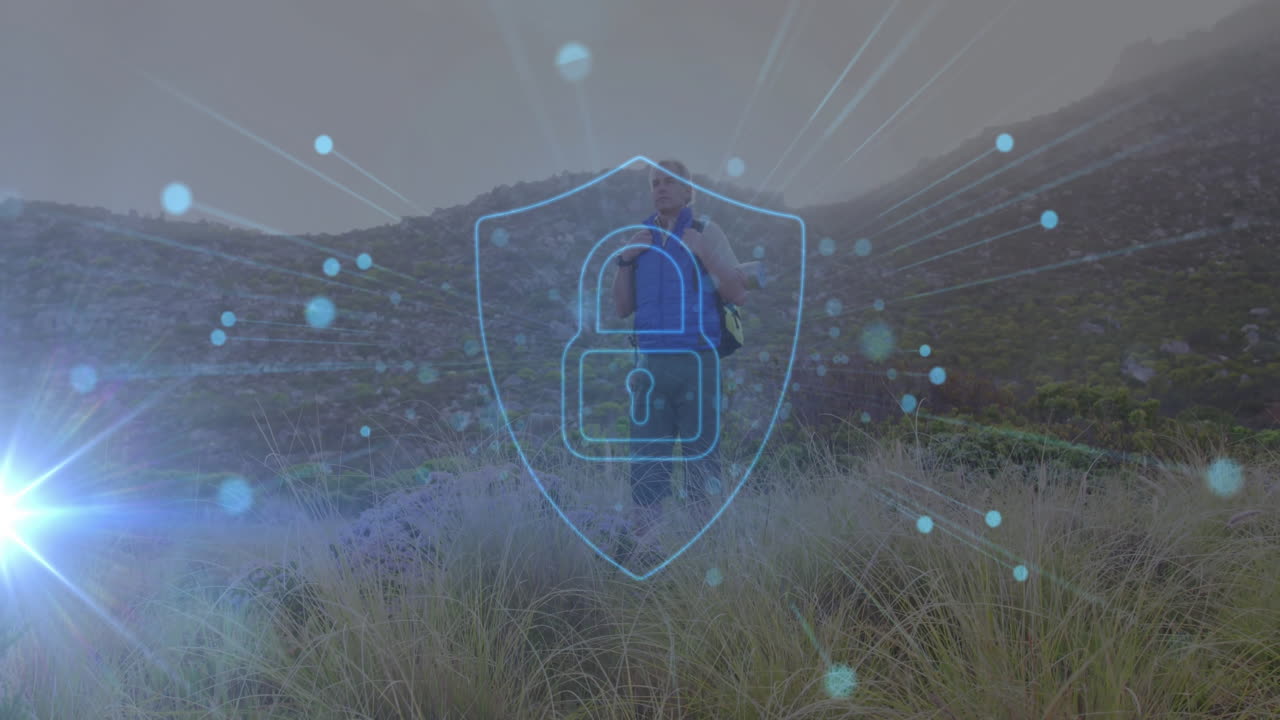 Mature male hiker gripping pack straps on grassy hill, displaying security shield for technology