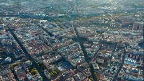 Aerial-panoramic-view-of-town-developments,-blocks-of-buildings-and-streets-lit-by-afternoon-sun.