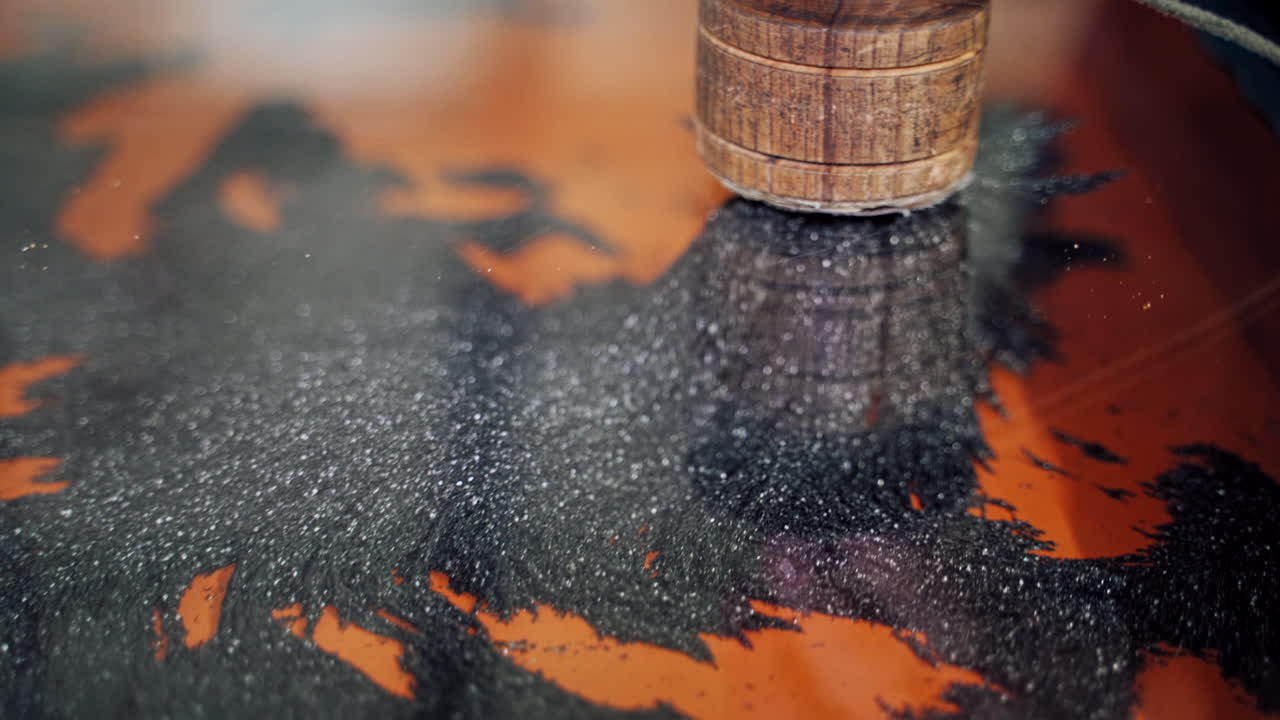 Hand holds brush and touches metallic filing on magnets. Iron shavings and magnet.