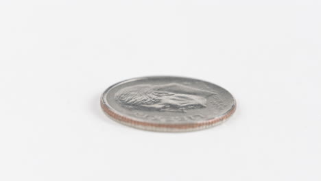 una moneda de diez centavos de plata colocada plana sobre una mesa blanca