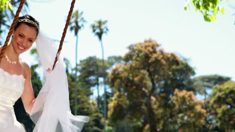 pretty bride sitting on a swing smiling at camera