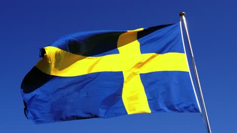 the swedish flag caught majestically waving on a clear summer day in the mariefred region