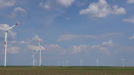 view on several windmills, wind generators, turbines, producing renewable clean energy by converting kinetic energy