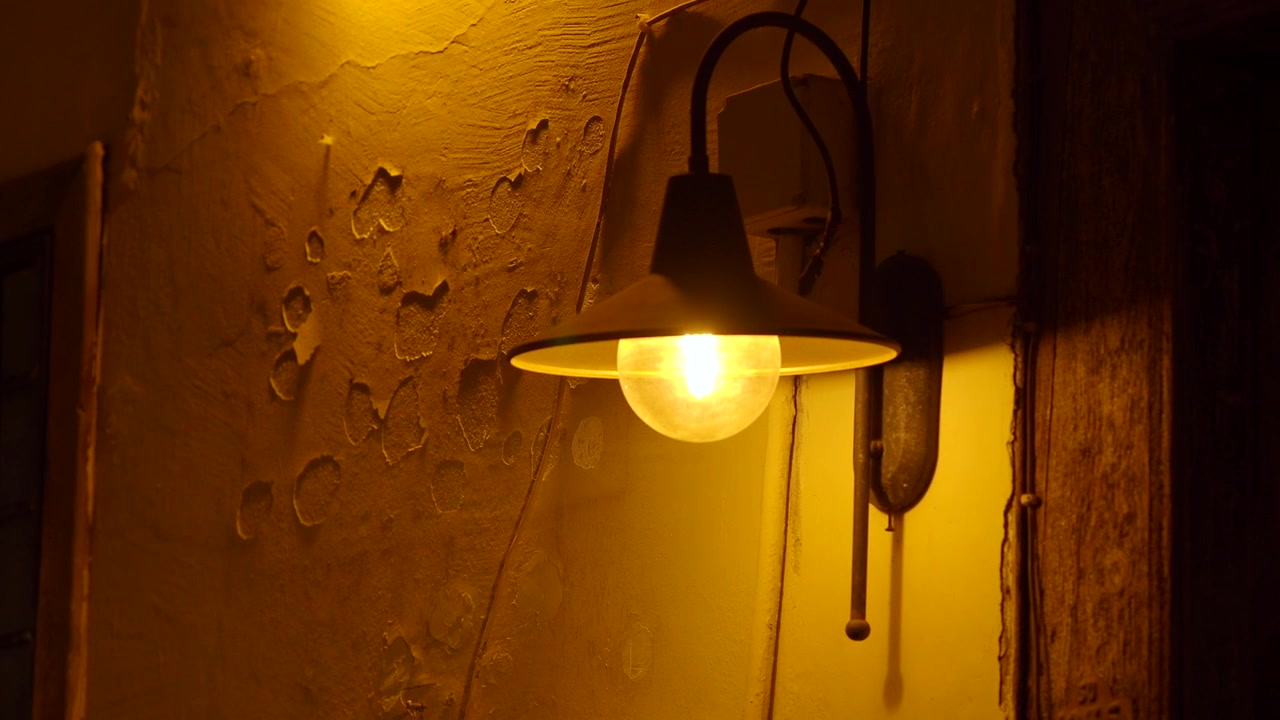 Lampu Dinding Vintage Menerangi Dinding Bertekstur dalam Cahaya Redup