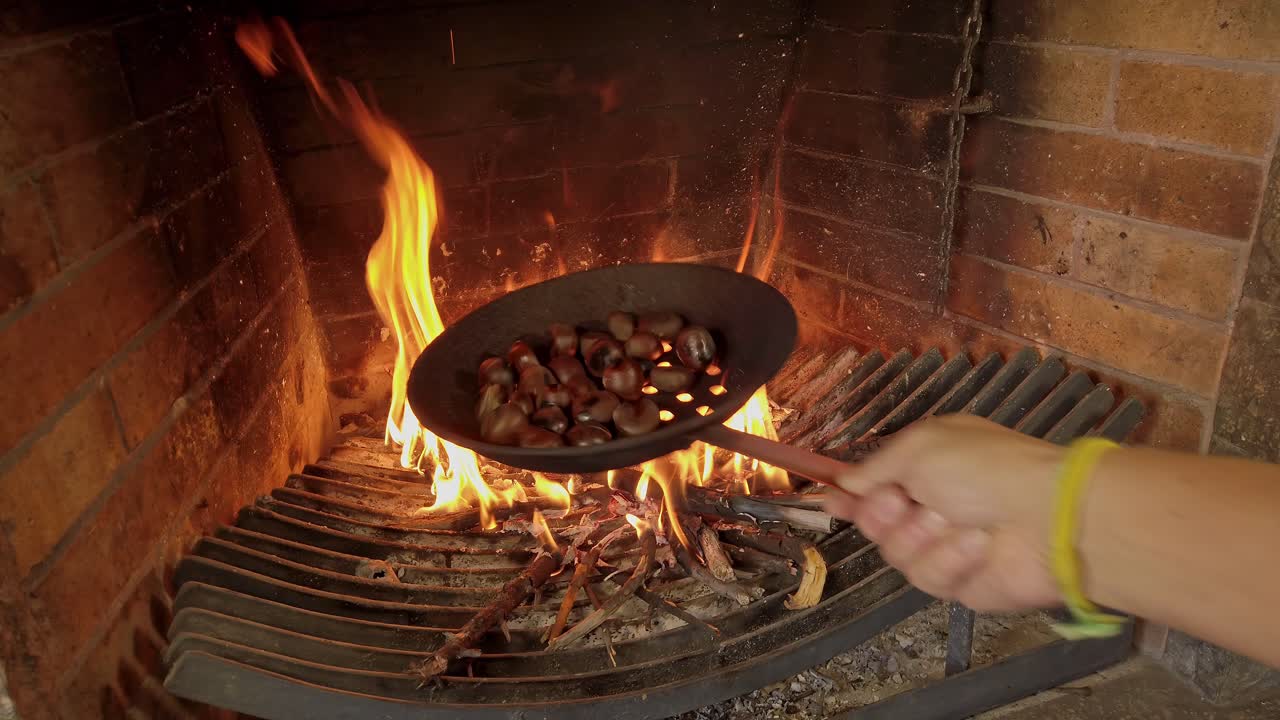 Close Up Shot of chef's Hand Cooking Chestnuts on the direct Fire of the Grill