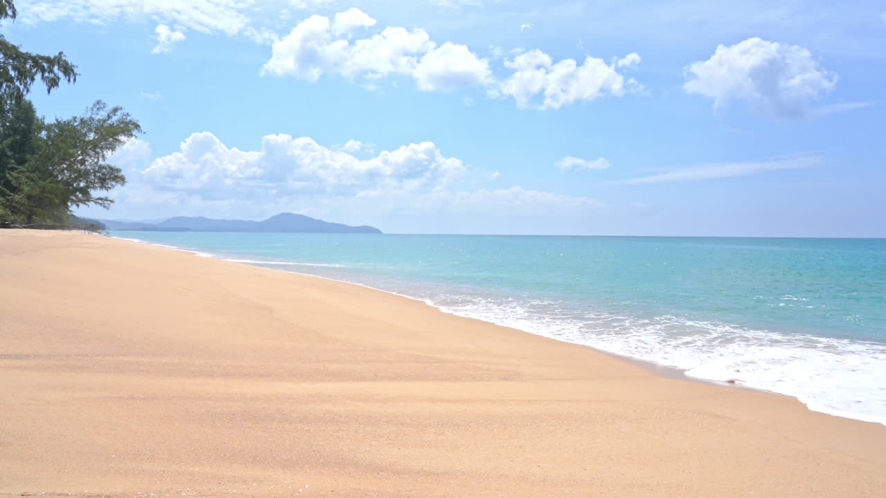 泡沫海浪涌向空旷的岛屿白沙滩，翡翠般宁静的海潮，多云天空，度假模板，极简留白空间。