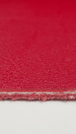 seam on edge of red color cow leather material on white cutting table macro view. material sheet in sewing workshop. design ideas and decorative techniques