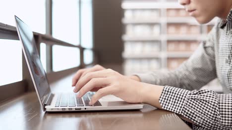 asian university student man using laptop computer in college library. young businessman typing on laptop keyboard in working space. freelance lifestyle or educational research concepts