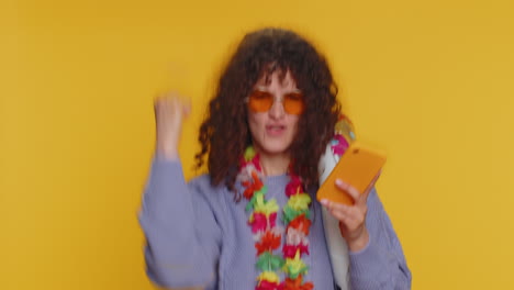 mujer con cabello rizado y gafas de sol toma una selfie en fondo amarillo