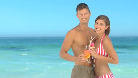 una pareja bebiendo cócteles en una playa.