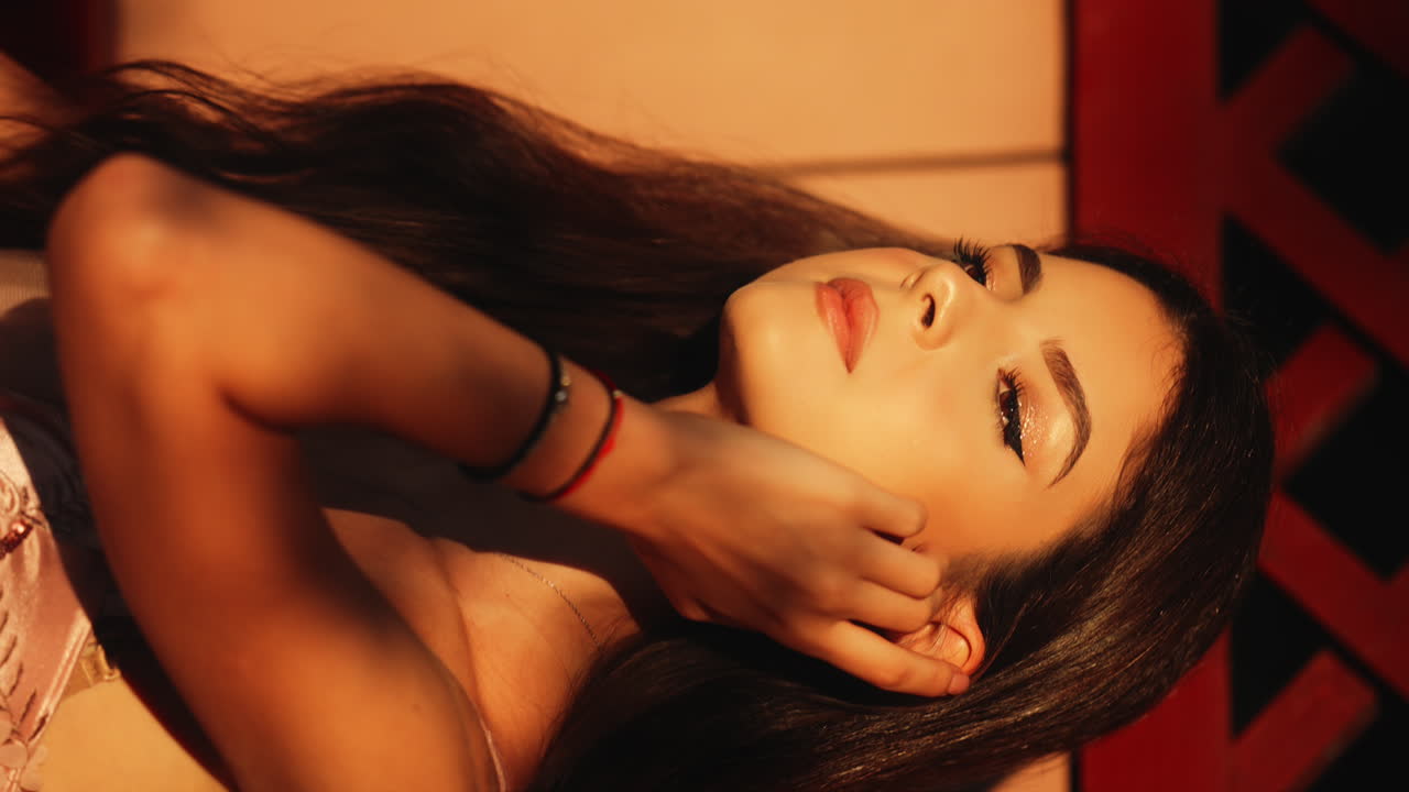 VERTICAL Seductive bronze female teasing long brunette hair posing in golden sunset lighting