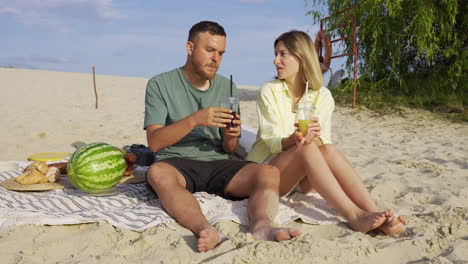 un couple fait un pique-nique sur la plage.