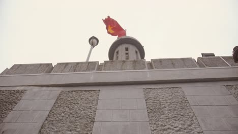 looking up to lũng cú flag tower behind wall with vietnamese flag fluttering in the wind