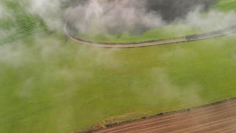 a morning with fog in a rural area of luxembourg with an unpaved road