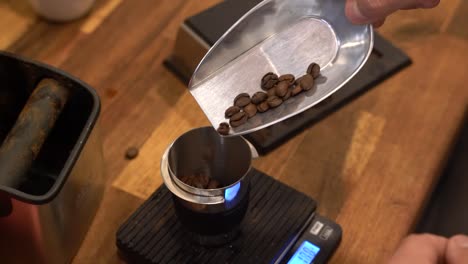 pesando granos de café tostados en una báscula para preparar una bebida de muestra en una tostaduría, primer plano manual