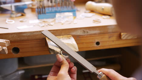 Close-Up-Of-Female-Jeweller-Working-On-Ring-With-File-In-Studio