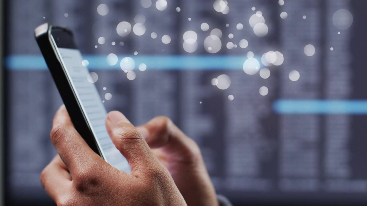 Male hands scrolling phone at tech desk, causing light particles obscuring cyan bars for review