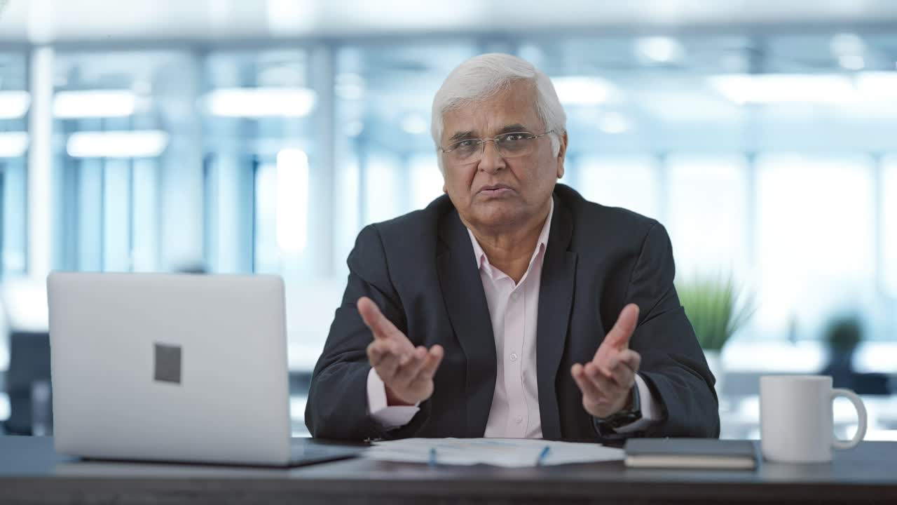 Serious senior Indian businessman talking to someone