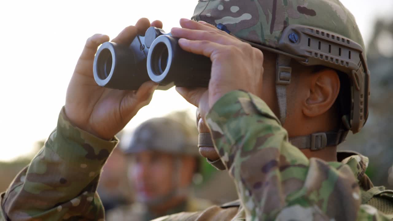 vista lateral de un joven soldado militar caucásico observando en el campo durante el entrenamiento militar 4k