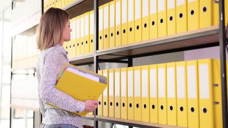 woman feeling overwhelmed while organizing or searching for documents in an office archive