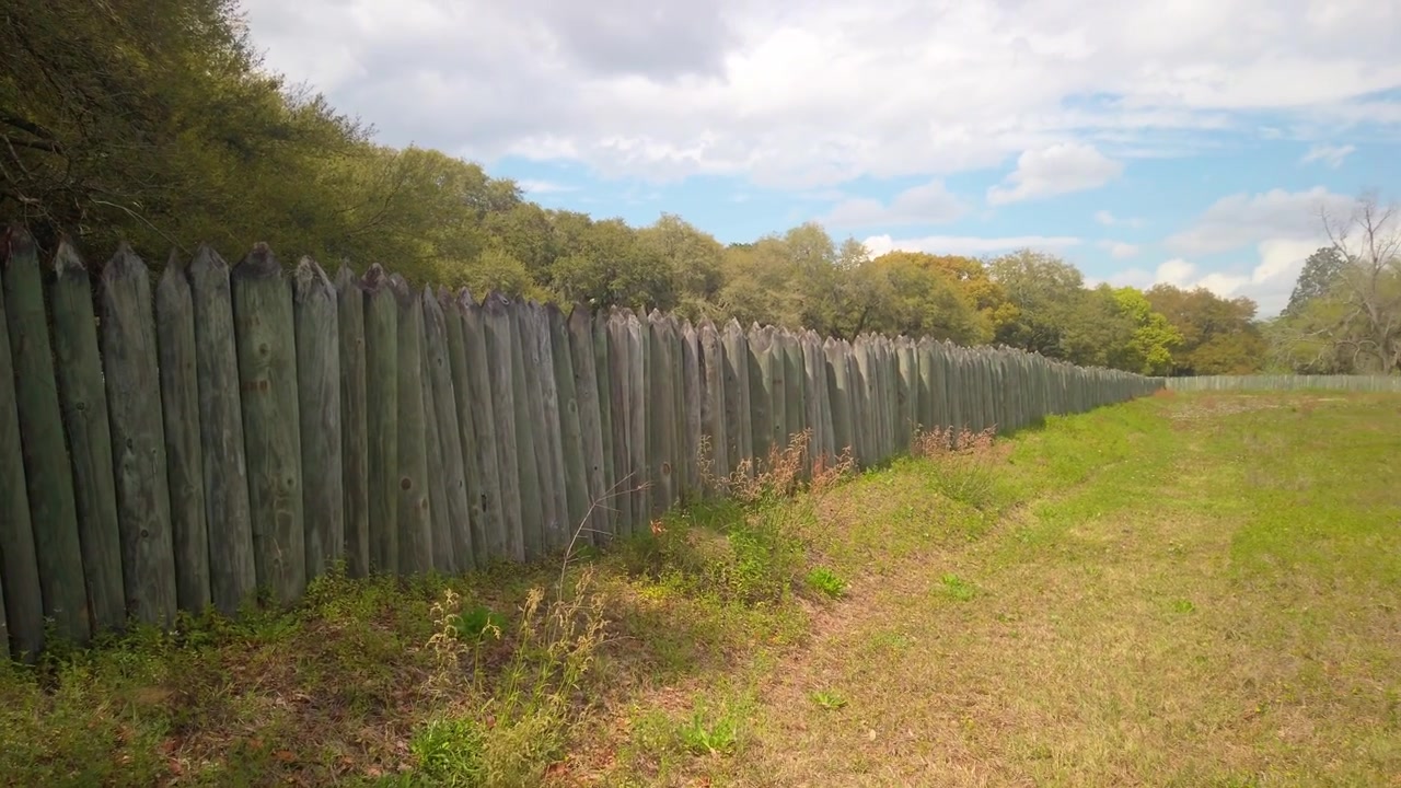 Toma panorámica amplia con gimbal de una valla de madera que marca los límites originales de Old Charles Towne Landing en Carolina del Sur. 4K