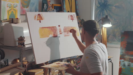 creative man painting picture with brush on canvas in art studio