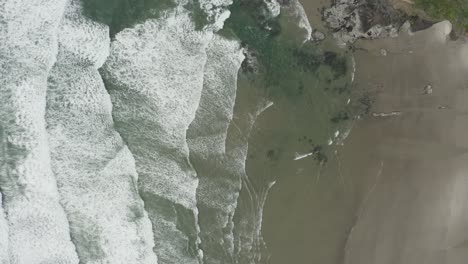 Stationäre-Drohnenaufnahme-Von-Meereswellen,-Die-Auf-Den-Strand-Treffen