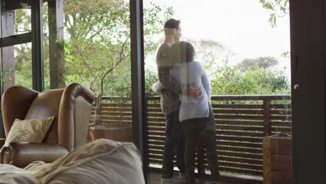 pareja feliz abrazándose y hablando, de pie en el balcón disfrutando de la vista en el campo