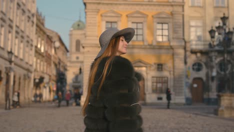 young woman with beautiful blue eyes in a gray hat walking city street with headphones