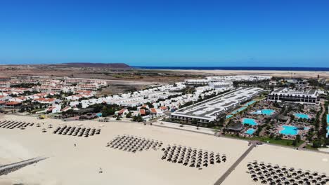 vista aérea de bikini playa sombrillas con resort y piscinas en segundo plano.