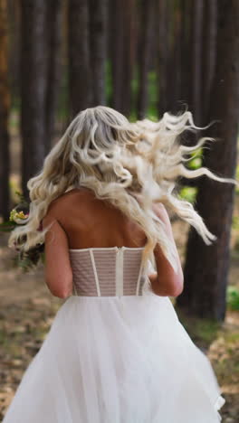 pretty young woman with festive hairdo in elegant wedding dress holds flowers bouquet running along green park with waving loose hair slow motion