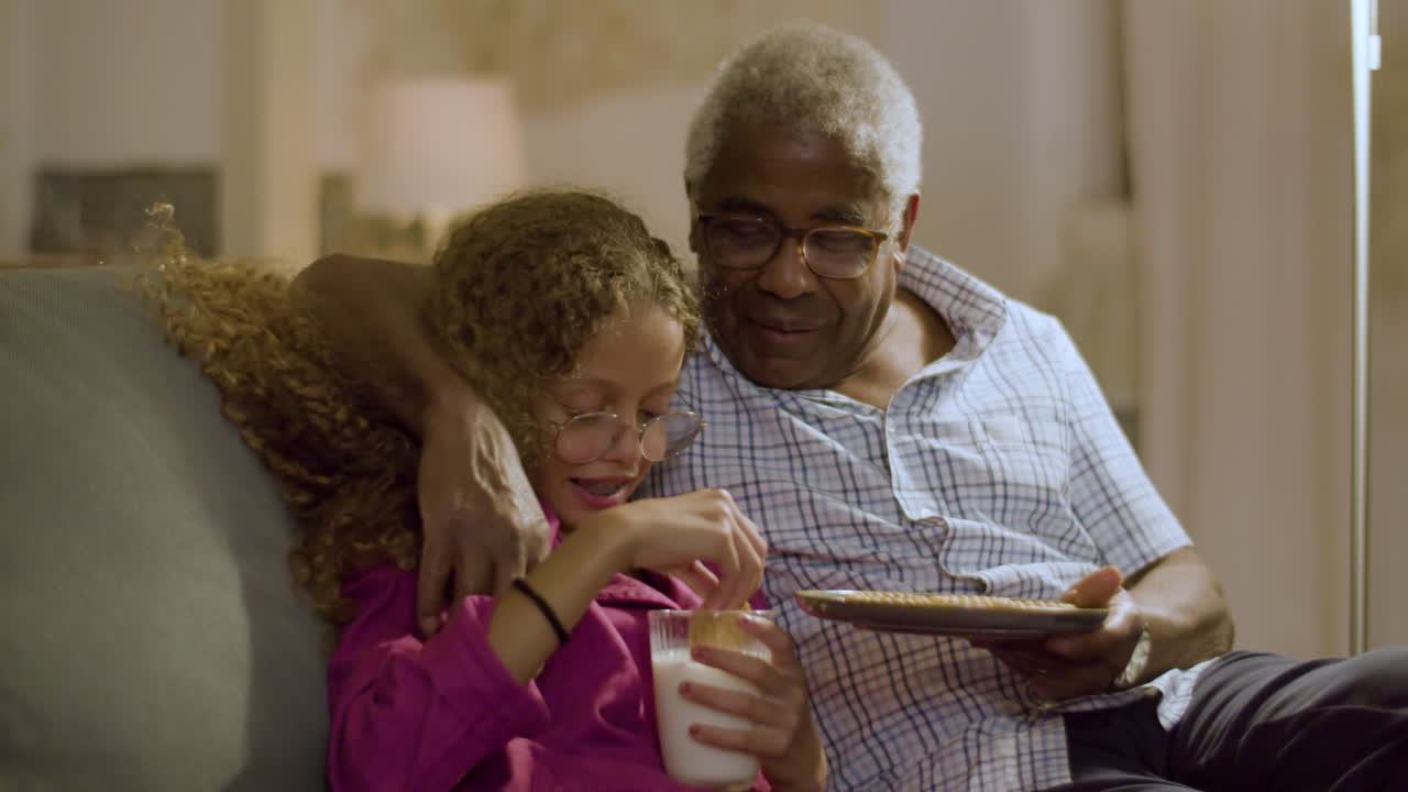 Young girl eating biscuits and drinking milk before going to bed