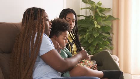 family watching tv and snacking on the couch