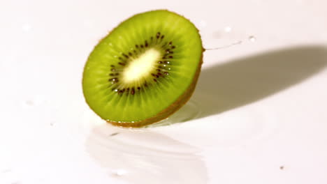 una rebanada de kiwi girando sobre una superficie húmeda