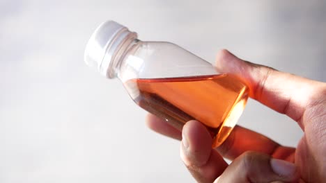 small orange liquid bottle in hand