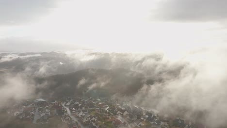 imágenes de drones de una urbanización en noruega con algo de niebla flotando en el aire y el sol iluminando las nubes