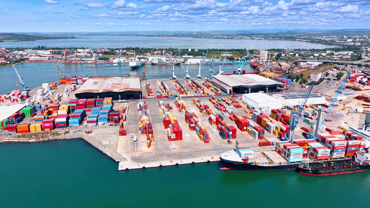 Burgas, Bulgaria, 1 May 2026: Wide Harbor View Of Industrial Container Terminal. Aerial panorama of industrial harbor with container terminal, cargo ship, cranes, blue water, and city background.
