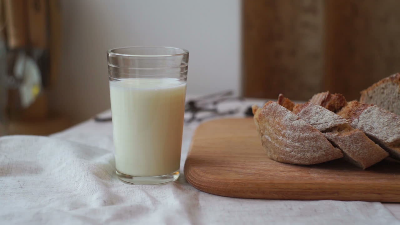 vaso de leche y rebanada de pan en tablero de madera. taza de leche y pan en rodajas