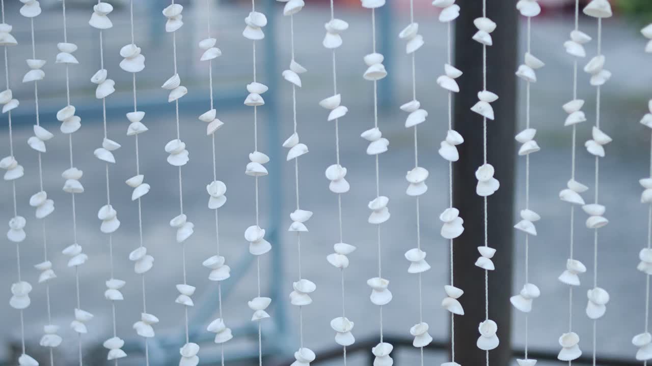 Shell decorations gently sway in the breeze, creating a calming atmosphere in a Phuket setting