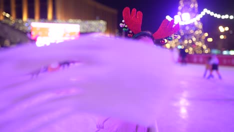 teenage girl ice skating at night with christmas decorations