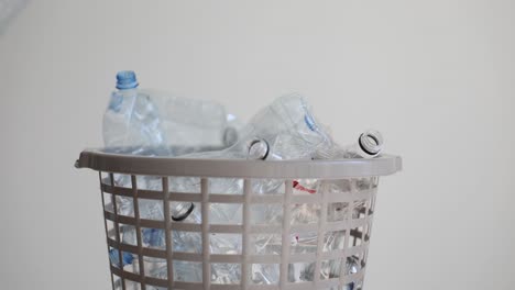 person putting plastic bottles into a recycling basket