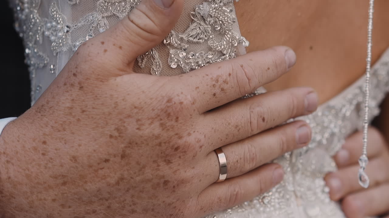 Evlilik yüzüklü damat, düğünde karısının açık sırtını okşar.
