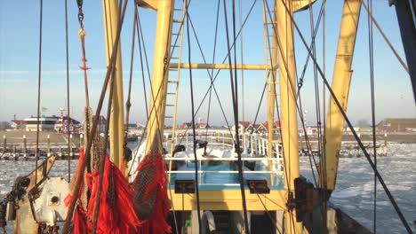 POV-Von-Der-Brücke-Eines-Fischerbootes,-Das-An-Einem-Sonnigen-Wintertag-In-Einen-Zugefrorenen-Hafen-Fährt