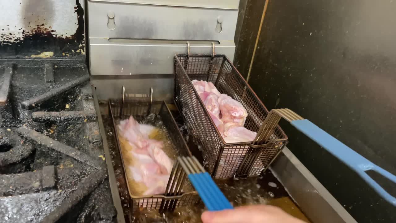 chicken wings fried in oil fryer of restaurant kitchen