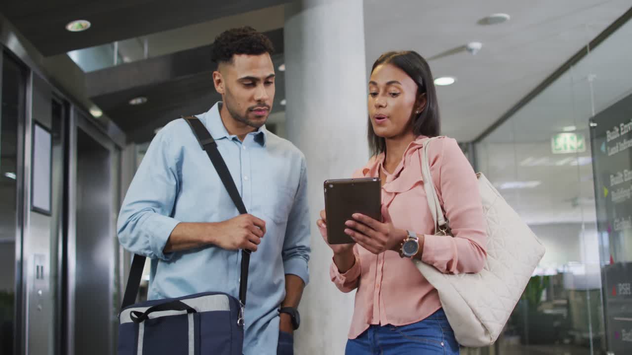 video de una mujer y un hombre de negocios diversos usando una tableta y hablando